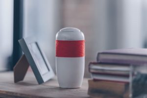 White urn with orange stripe, sitting on nightstand at home