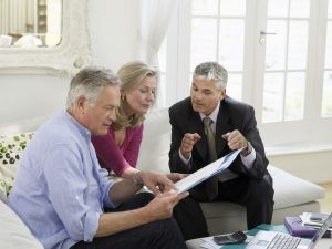 Mature husband and wife sitting at home reviewing funeral options with funeral director