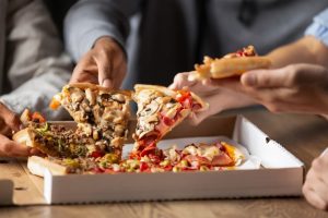 Several people sitting down together and eating a pizza out of the box