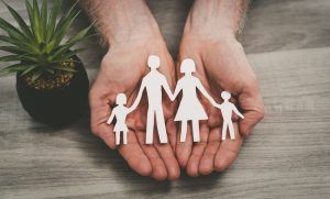 Person's hands holding a family made out of paper