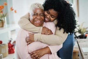 daughter and elderly mother hugging and laughing