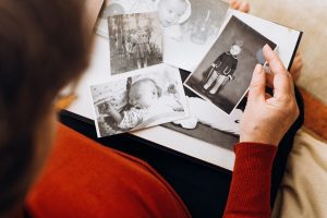 Woman in red shirt sitting down and looking at old, black and white photos