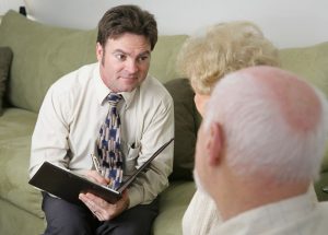 Attentive funeral director sitting on couch as he listens to older couple talk