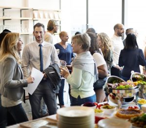 Group of people at a reception, talking with each other and eating food