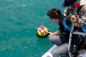 Family on boat setting our memorial flowers and scattering a loved one's ashes