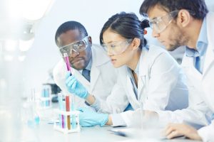 Three medical students looking at a test tube of blood