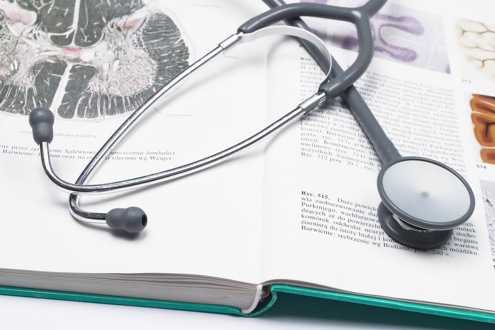 Open medical textbook with stethoscope lying on top