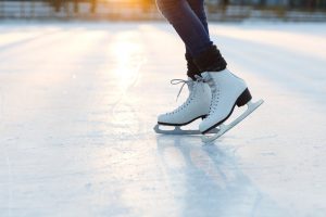 Focus on calves and feet of a person wearing ice skates and standing on an ice rink