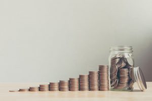 stacks of coins organized from smallest to largest with a jar of coins at the end