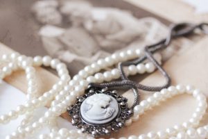 Heirloom cameo necklace with pearls laying on top of a black and white photo