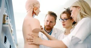 Three medical students learning about the anatomy of the whole body