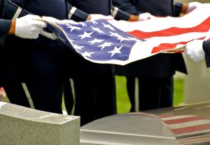 Servicemembers symbolically folding an American flag at a funeral