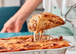 person scooping a slice of lasagna out of a dish