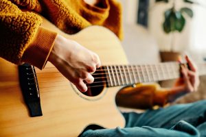 Person in yellow sweater playing the guitar and making music