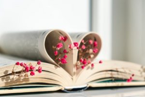 Book with pages bent into a heart shape with pretty red flower accents