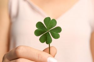 Woman in white shirt holding a shamrock for St. Patrick's Day