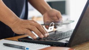 Man standing at computer typing in password; lock on screen denotes privacy and protected password