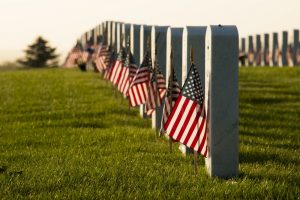 Row of veteran grave stones with American flags planted beside each one