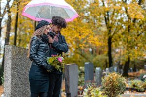 Young man and woman wearing black and visiting a loved one's grave