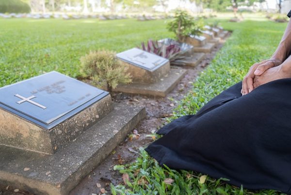 Woman kneeling in front of a slant or bevel grave marker