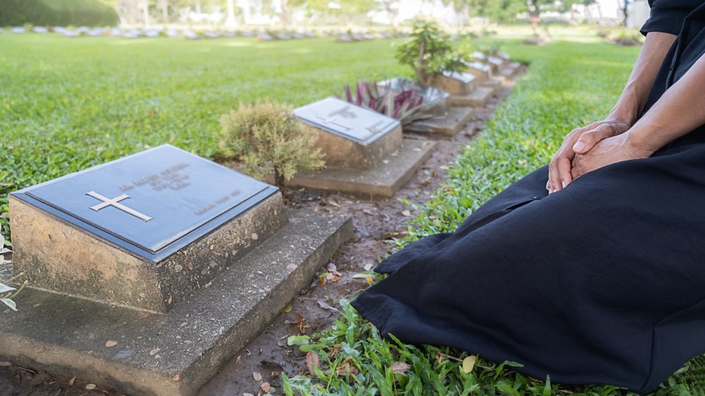 Woman kneeling in front of a slant or bevel grave marker