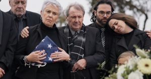 Grieving family holding American burial flag as they stand at graveside