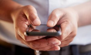 Focus on man's hands as he holds a smartphone