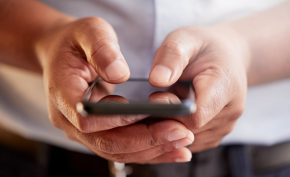 Focus on man's hands as he holds a smartphone
