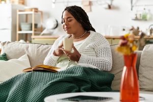 Woman sitting at home with a cup of tea and a book