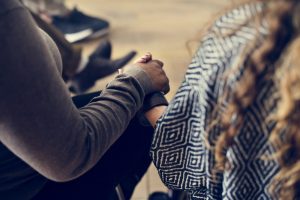 Two female friends holding hands during a grief counseling session