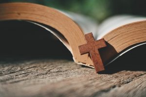 Small wooden cross propped against a books of hymns or other spiritual book