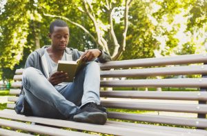 Man resting on bench with book, taking it easy