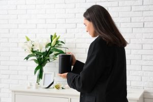 Woman in black jacket holding an urn, remembering and honoring the life of a special person