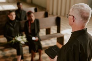 Mourners listening to a priest or pastor at a funeral