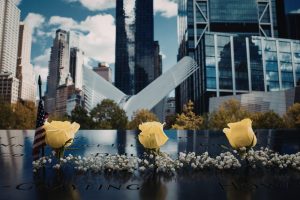 Three yellow roses resting on 9/11 memorial plaque