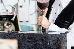 Craftsperson using a chisel and mallet to carve a headstone