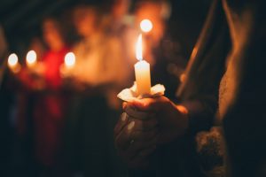 Woman attending a community vigil, holding a candle of remembrance