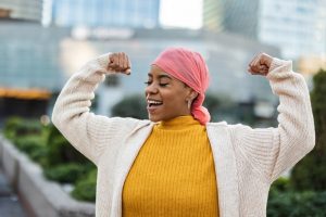 Woman with pink scarf holding up arms in a position of victory and strength
