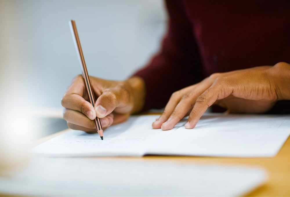 Person writing ideas for an epitaph in a notebook