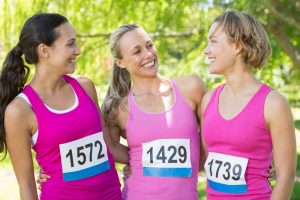 Three women wearing pink shirts and participating in a 5K to raise awareness and donations