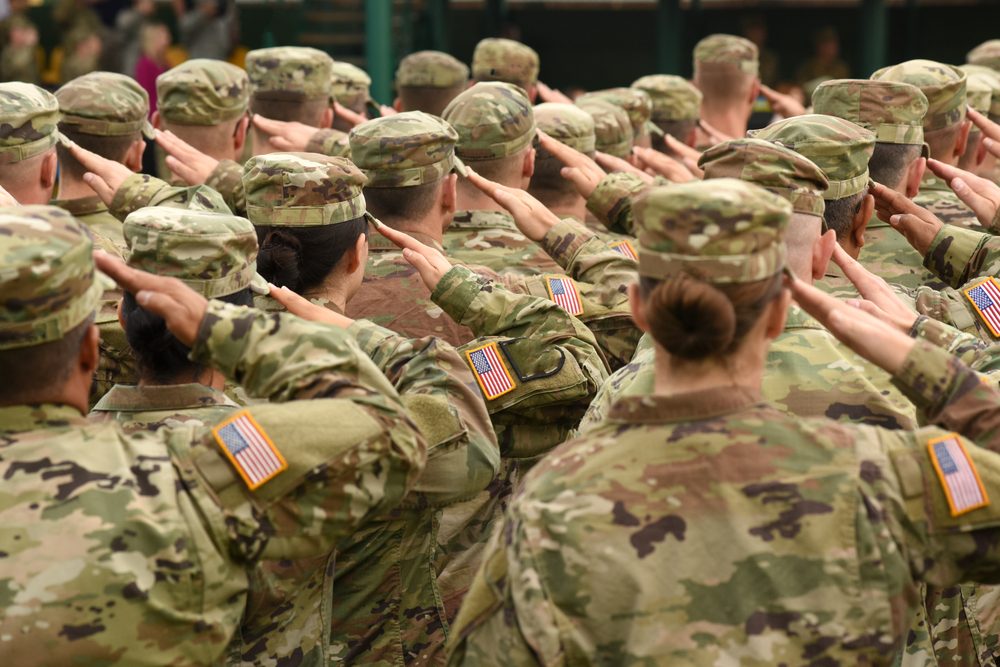 Men and women in fatigues, saluting, backs to the camera