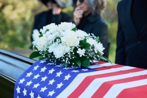 Spray of white flowers resting on a casket covered in an American flag