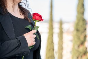 Woman in black holding red rose near her heart