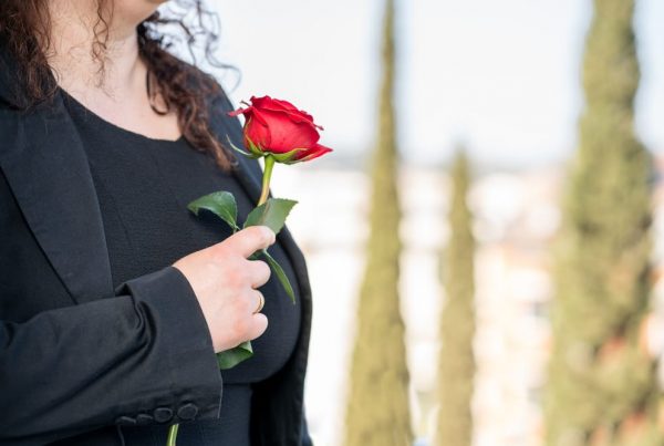 Woman in black holding red rose near her heart