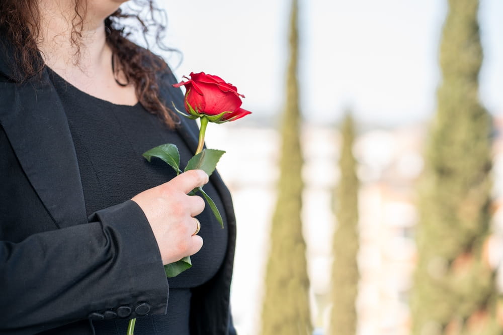 Woman in black holding red rose near her heart