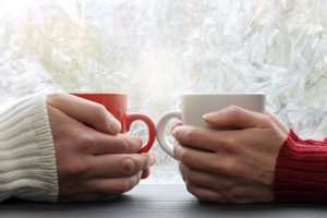 Focus on hands of two people as they hold mugs
