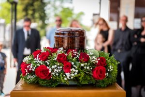 Memorial service with urn surrounded by white roses and greenery