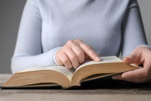 Woman in gray sweater reading a book