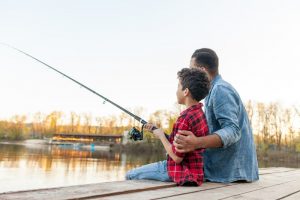 Father and son sitting on dock and fishing together