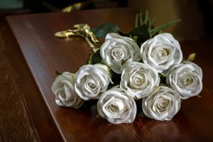 White flowers resting on dark wood casket